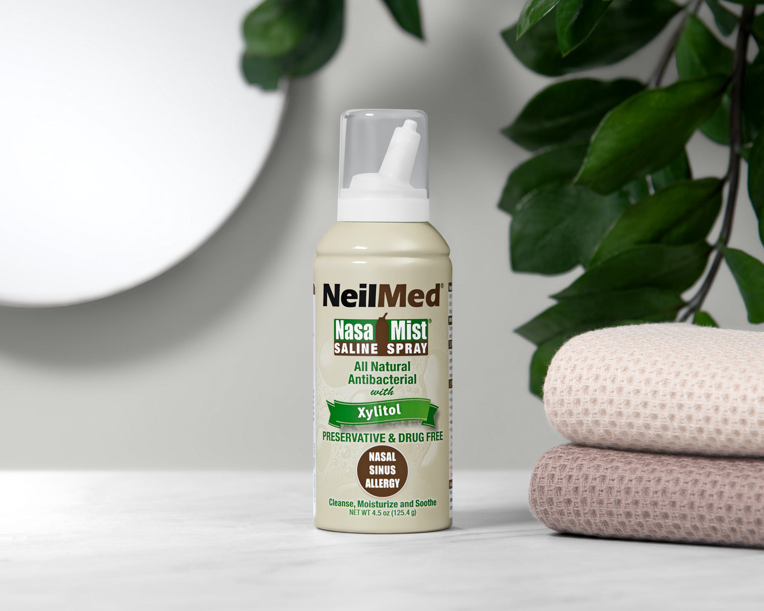 NeilMed nasal spray bottle on a surface with a plant in the background
