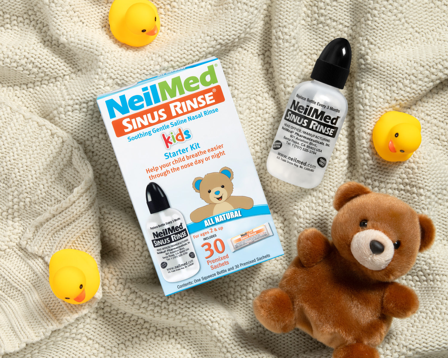 NeilMed Sinus Rinse kids starter kit with bottles and a teddy bear on a textured surface.