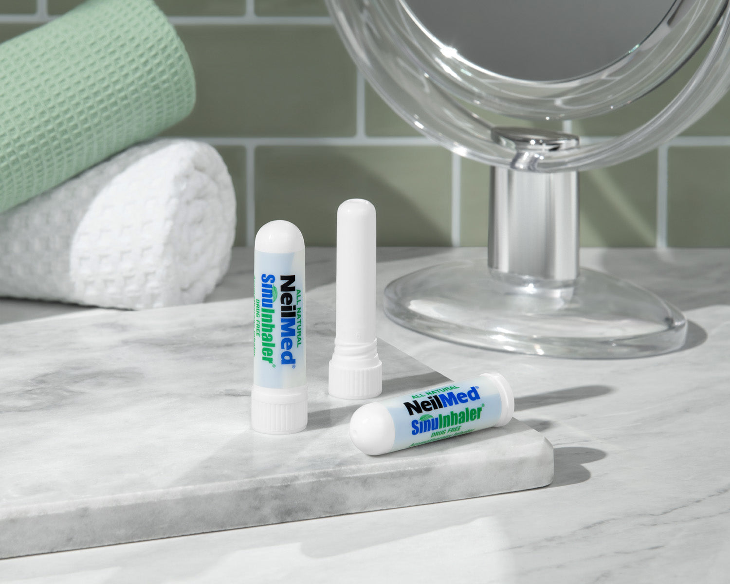 Three NeilMed SinusInhaler products on a marble surface with a mirror in the background.