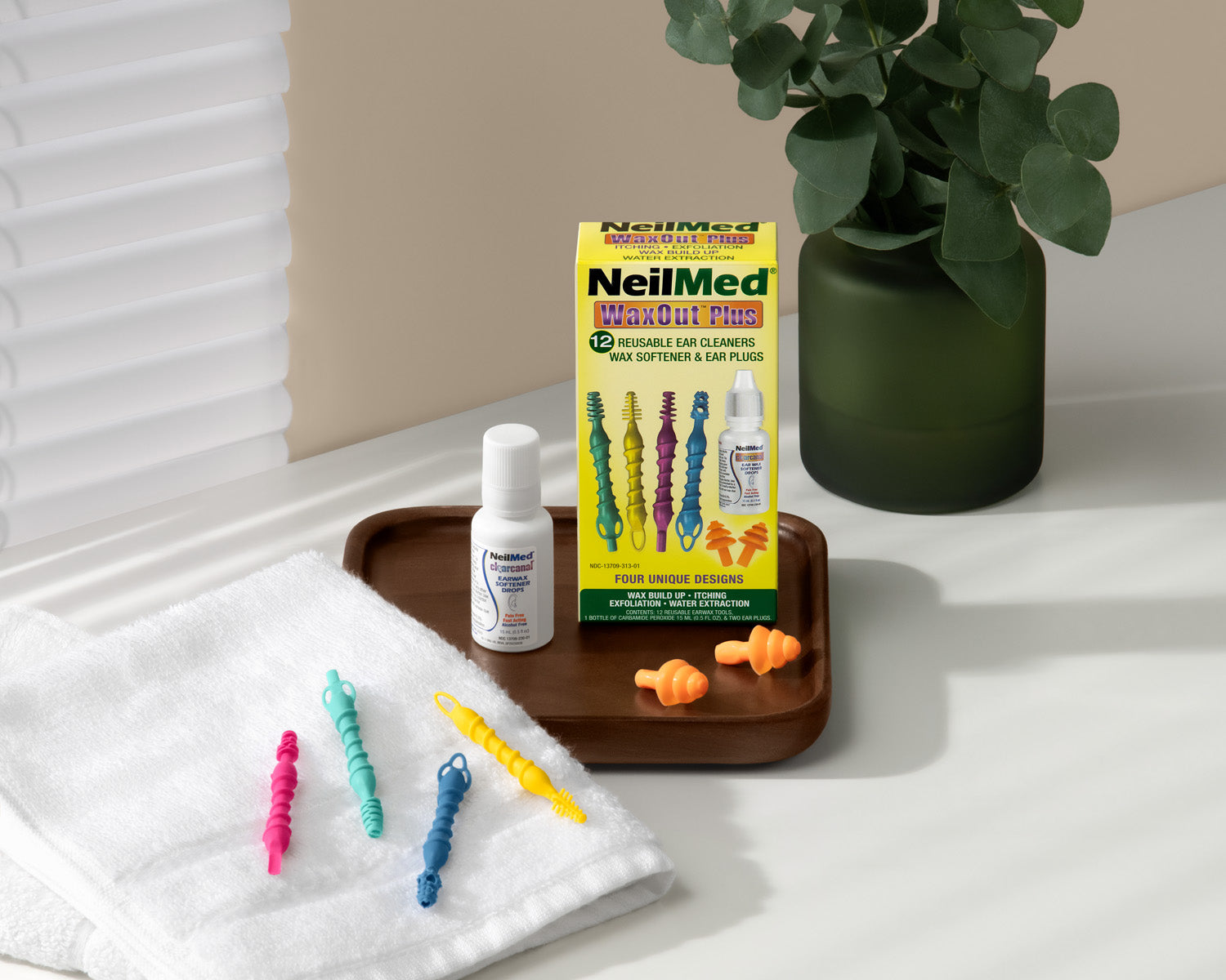 Waxout plus on a white counter top and green vase with plant in it