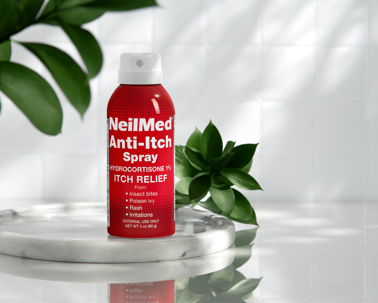 Red NeilMed Anti-Itch Spray bottle on a white surface with green leaves in the background