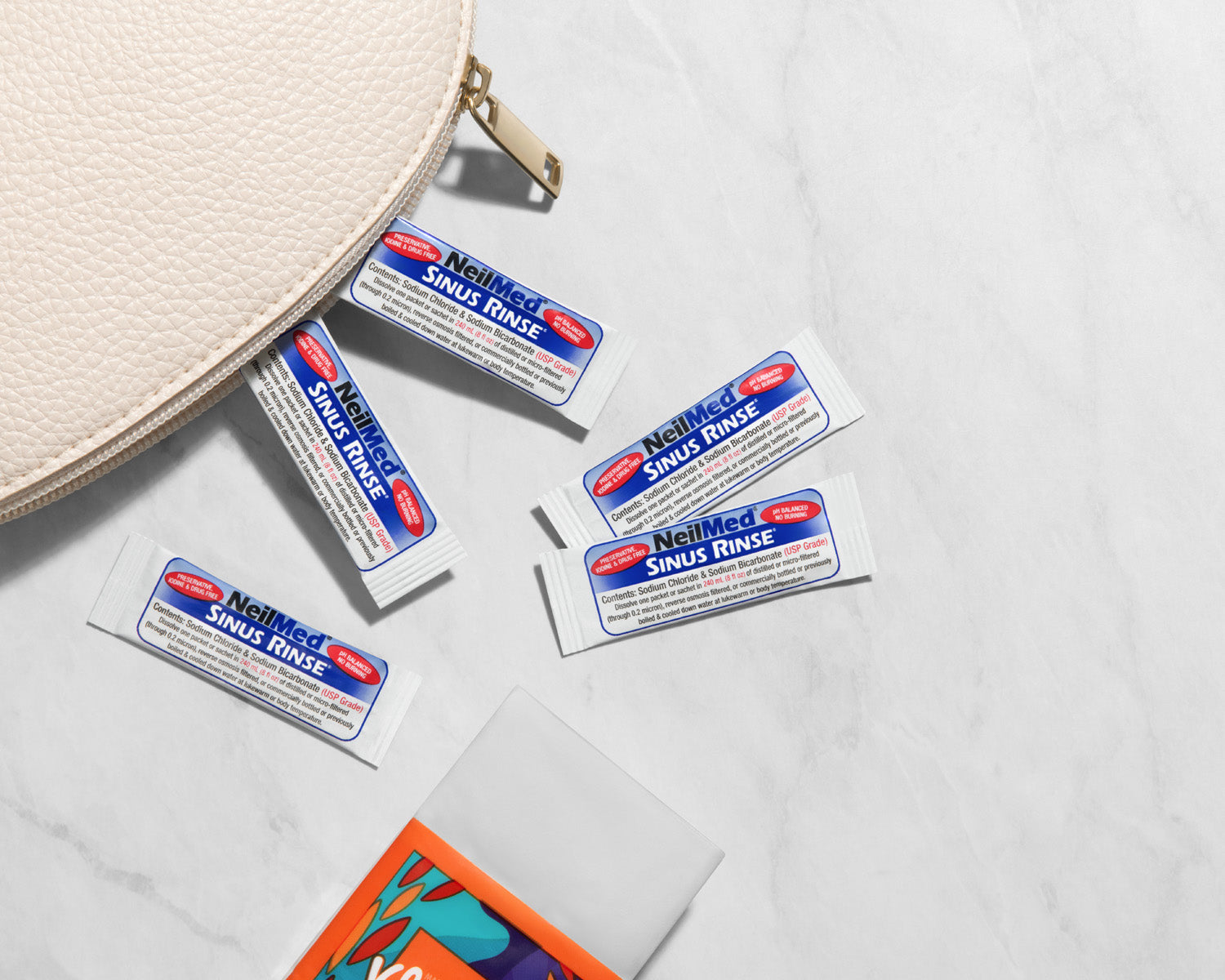 Neuland Sinus Rinse packets on a light gray surface with a beige round container.