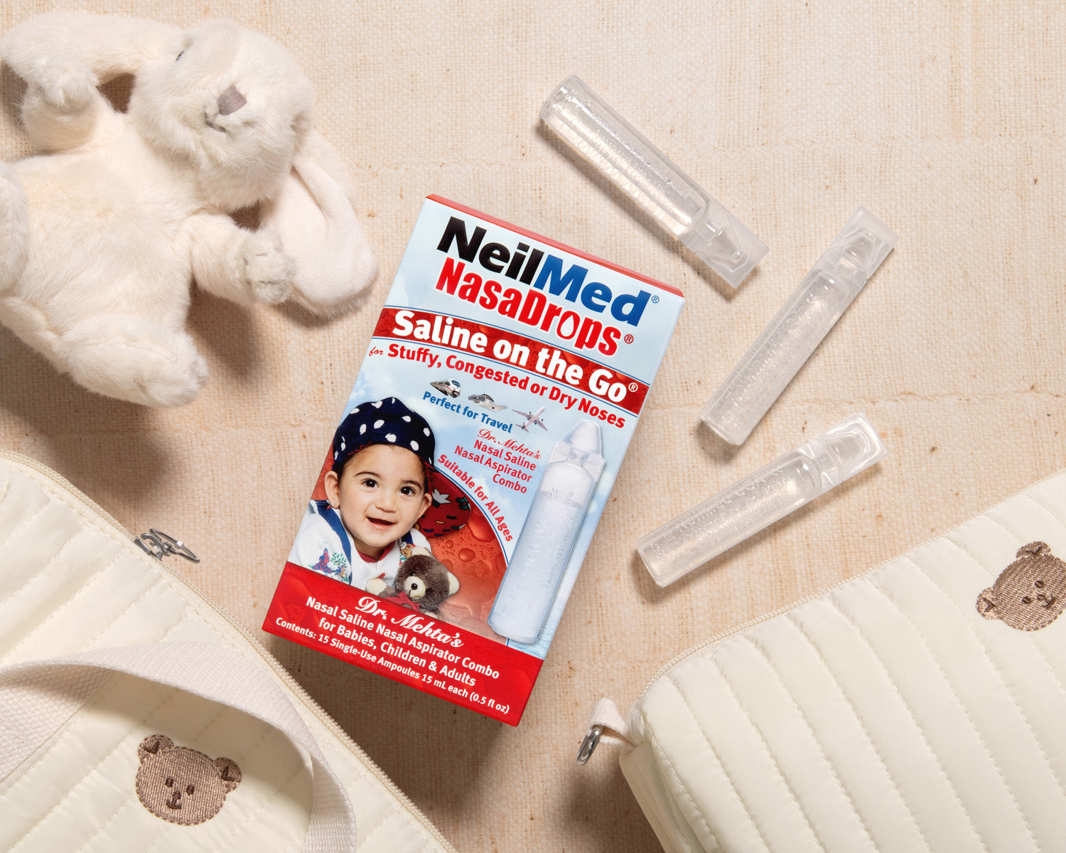 NeilMed NasalDrops packaging with saline bottles on a beige surface with teddy bears.